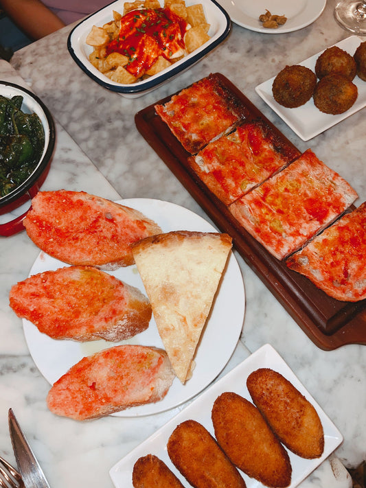 Spanish tapas spread — pan con tomate, patatas bravas and croquetas on a table