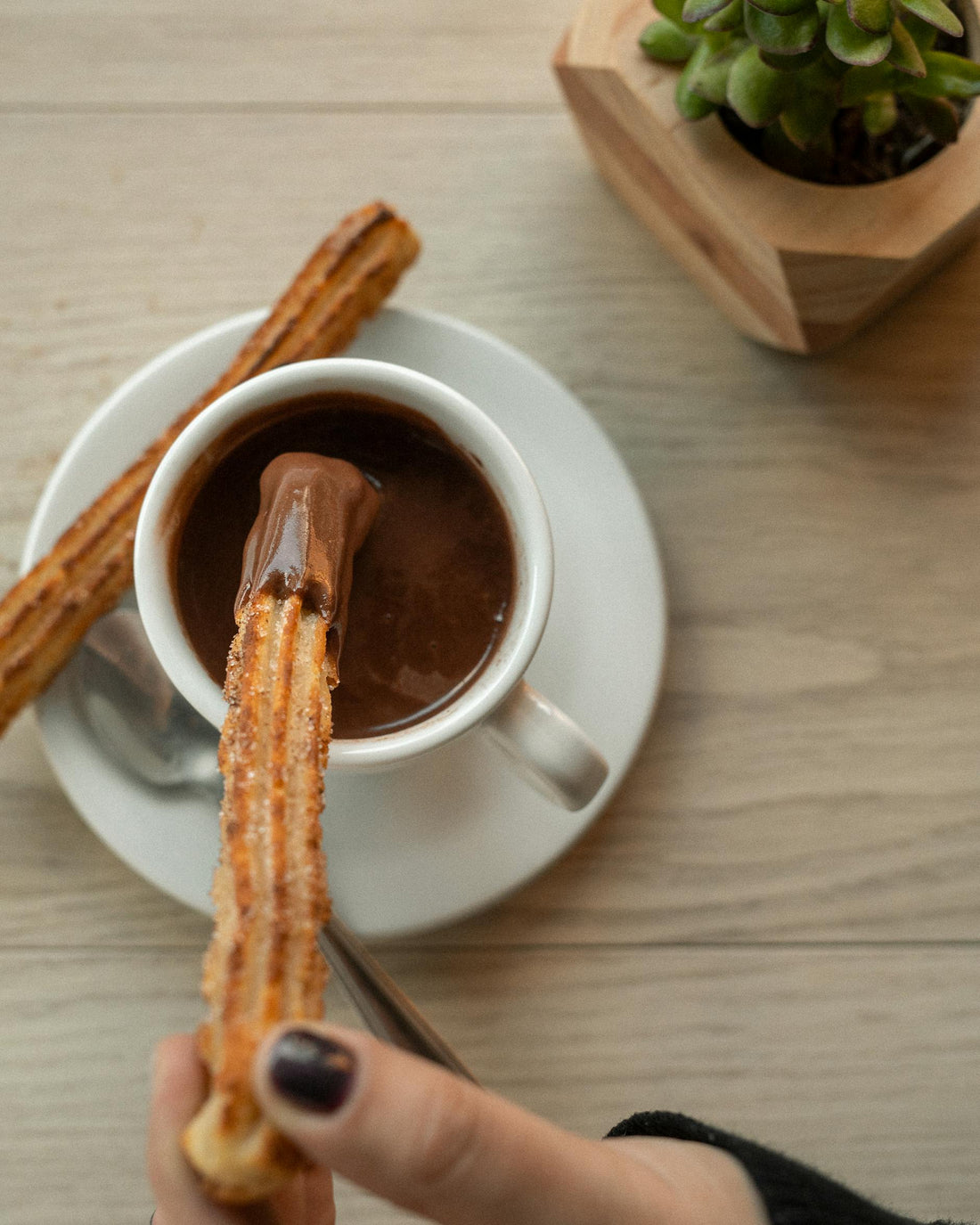 Thick Spanish hot chocolate (chocolate a la taza) with a churro being dipped