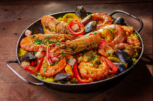 A traditional Spanish seafood paella (paella de marisco) with prawns, mussels and red pepper in a paella pan