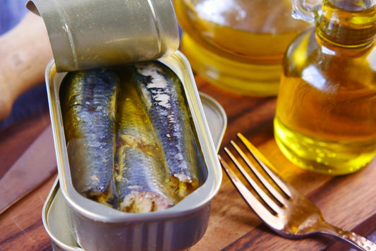 Open tin of Spanish fish conserva in extra virgin olive oil, served with a fork